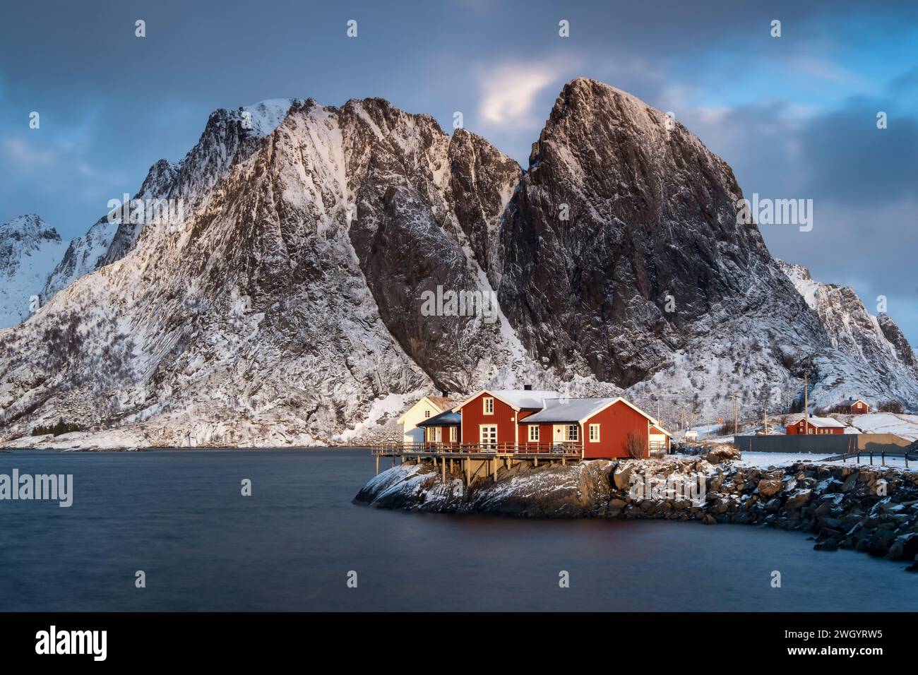 Rotes norwegisches Rorbuer-Haus und Festhaeltinden-Berg im Winter, reine, Moskenes Municipality, Nordland County, Lofoten Islands, Norwegen Stockfoto