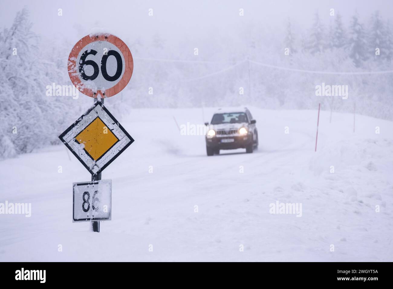 Auto, das 60 km/h und Priority-Straßenschilder bei eisigen Fahrbedingungen auf einer Autobahn in Senja, Norwegen, Skandinavien, Europa überquert Stockfoto