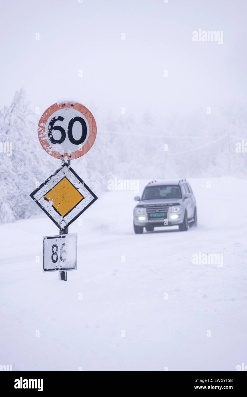 4x4-Fahrzeug, das eine 60 km/h und Priority-Straßenschilder bei eisigen Fahrbedingungen auf einer Autobahn in Senja, Norwegen, Skandinavien und Europa passiert Stockfoto