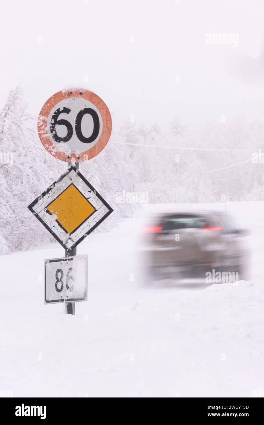 Rasantes Auto, das 60 km/h und Priority-Straßenschilder bei eisigen Fahrbedingungen auf einer Autobahn in Senja, Norwegen, Skandinavien, Europa überquert Stockfoto