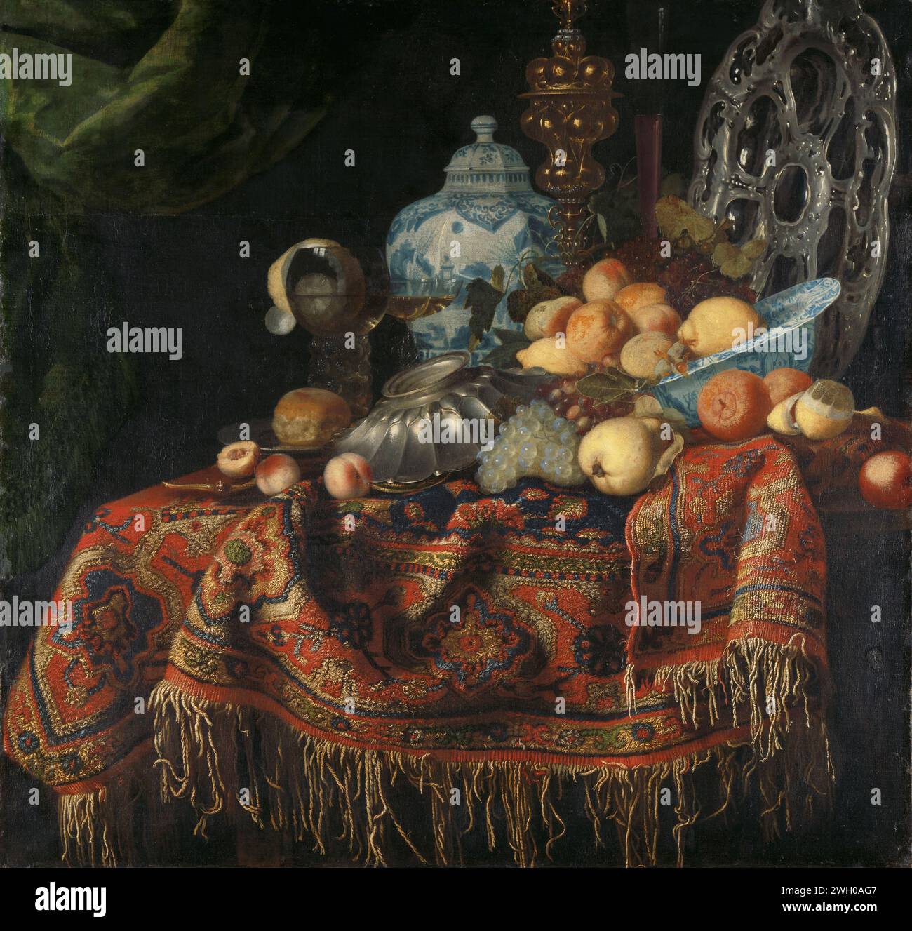 Stillleben mit Früchten, Tellern und Geschirr auf einem Putenteppich, Simon Luttichuys (zugeschrieben), 1650–1680 Gemälde Stillleben mit Früchten und Gefäßarbeiten auf einem Smyrna-Teppich. Auf einem Tisch, der mit einem orientalischen Teppich bedeckt ist, befinden sich eine Wan Li-Skala mit Äpfeln und Zitronen, silberne Schüsseln, eine goldene Vitrine, ein Brot auf einem Zinnteller, ein roemer mit Wein, in dem eine geschälte Zitrone, weitere Trauben und eine Birne enthalten sind. Auf der Rückseite befindet sich eine große Porzellanvase oder ein Topf. Nordholländische Leinwand. Ölfarbe (Lack) Tischtuch. Früchte: Zitrone. Früchte: apfel. Früchte: Pfirsich. Früchte: Traube. Lebensmittel; Stillleben von Lebensmitteln. Gelegt Stockfoto