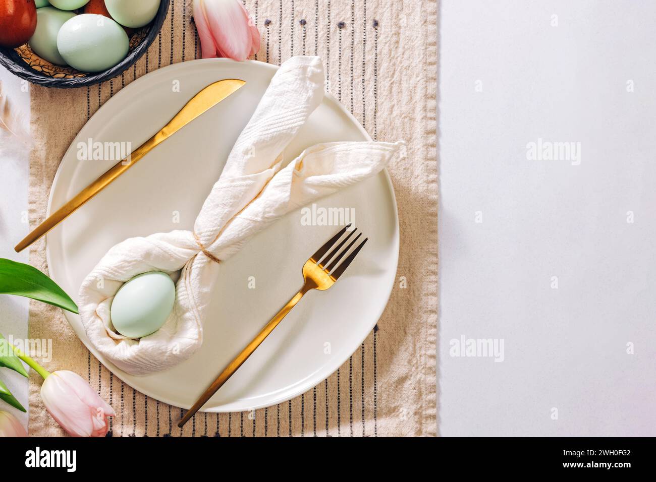 Tisch mit Ostermotiv, Serviette in Form eines Kaninchens und eines blauen Eies, Blick von oben Stockfoto