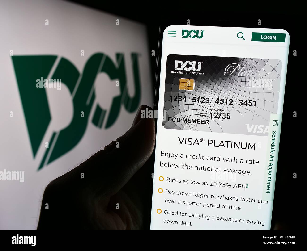 Person mit Smartphone und Webseite des Finanzinstituts Digital Federal Credit Union (DCU) mit Logo. Konzentrieren Sie sich auf die Mitte des Telefondisplays. Stockfoto