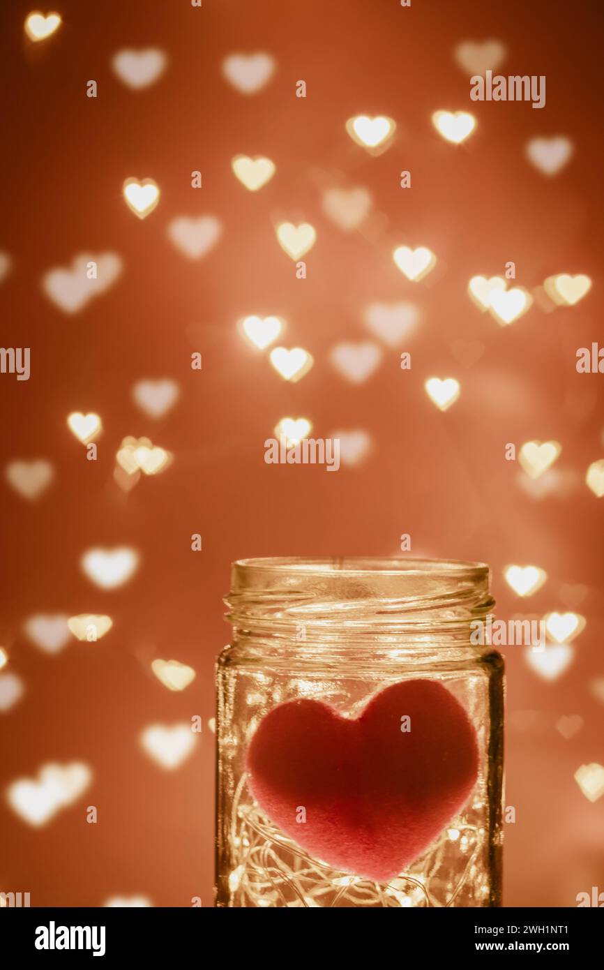 Glasgefäß mit warmem LED-Licht und rotem Herz innen, hell im dunklen Hintergrund mit herzförmigem Unschärfe-Bokeh-Licht dekorieren für Valentinstag Stockfoto