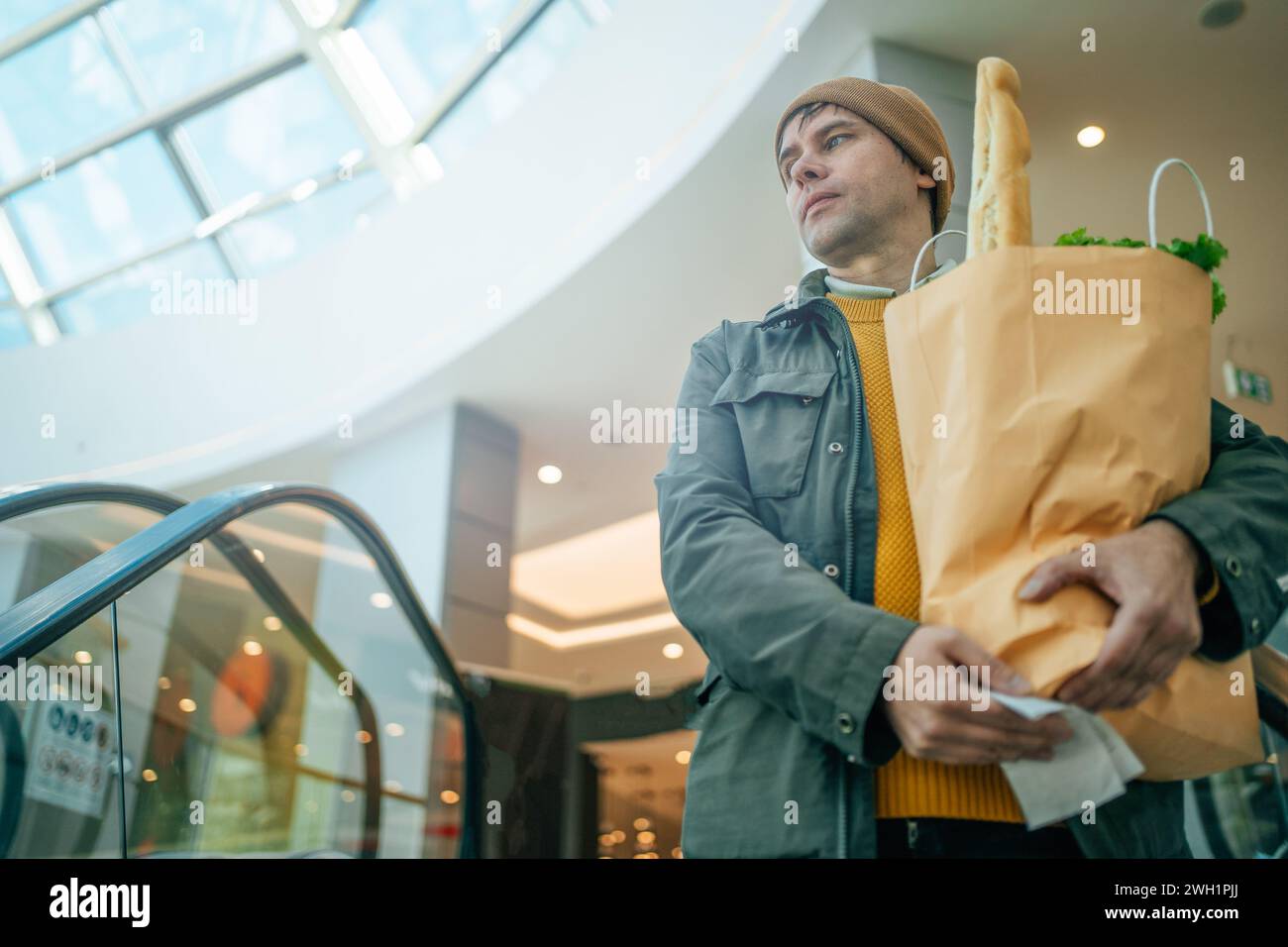 Der Mann hält eine Papiertüte mit verschiedenen Lebensmitteln in der Hand in der Mall Stockfoto