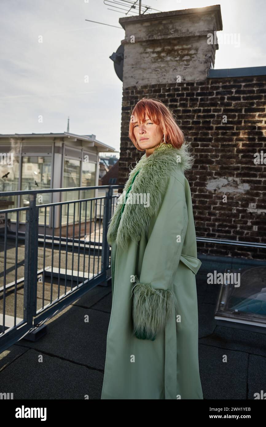 Attraktive Reisende in stilvoller Kleidung, die auf der Dachterrasse in Wien, Österreich, wegblickt Stockfoto