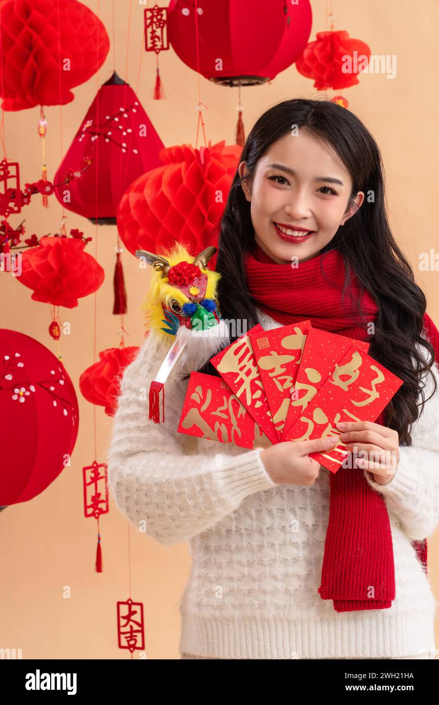 Neujahrsgrüße, eine junge asiatische Frau, die einen roten Umschlag hält Stockfoto