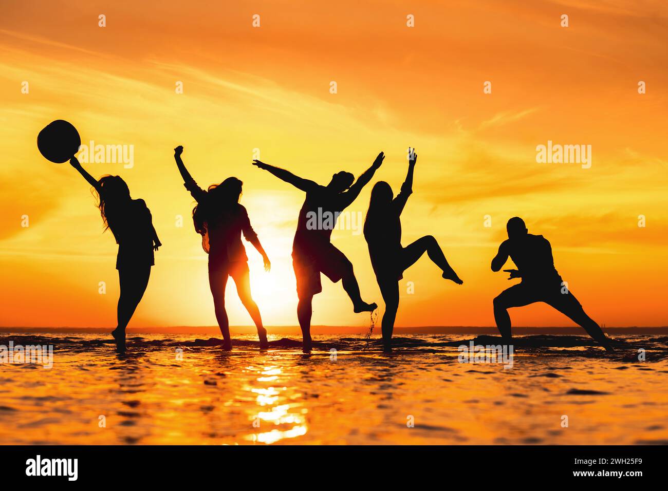 Eine Gruppe junger Freunde hat Spaß am Sonnenuntergang Strand. Lustige Silhouetten glücklicher Touristen Stockfoto