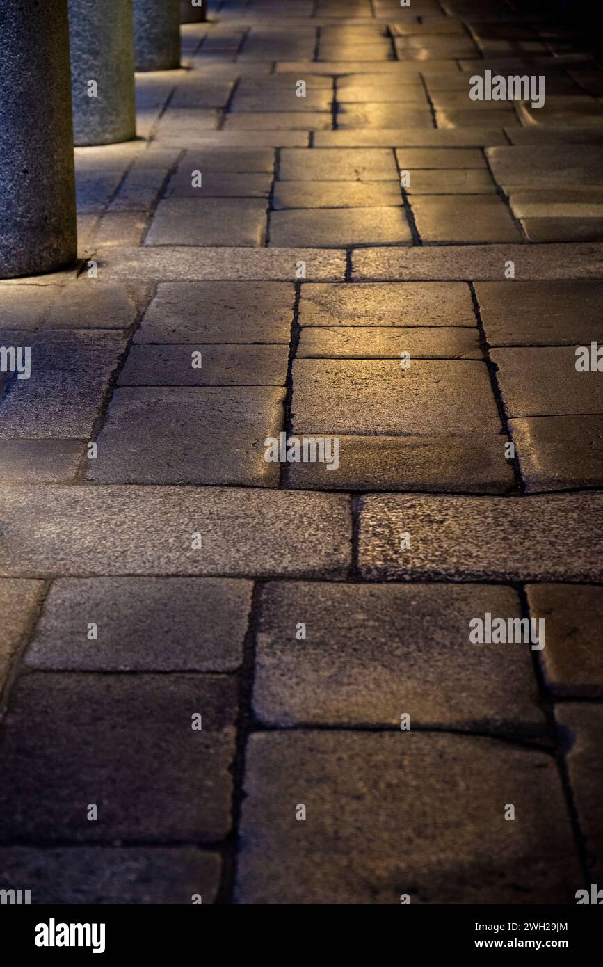 Arkadenpflaster aus Steinplatten, die in künstlichem Licht glänzen, London Stockfoto