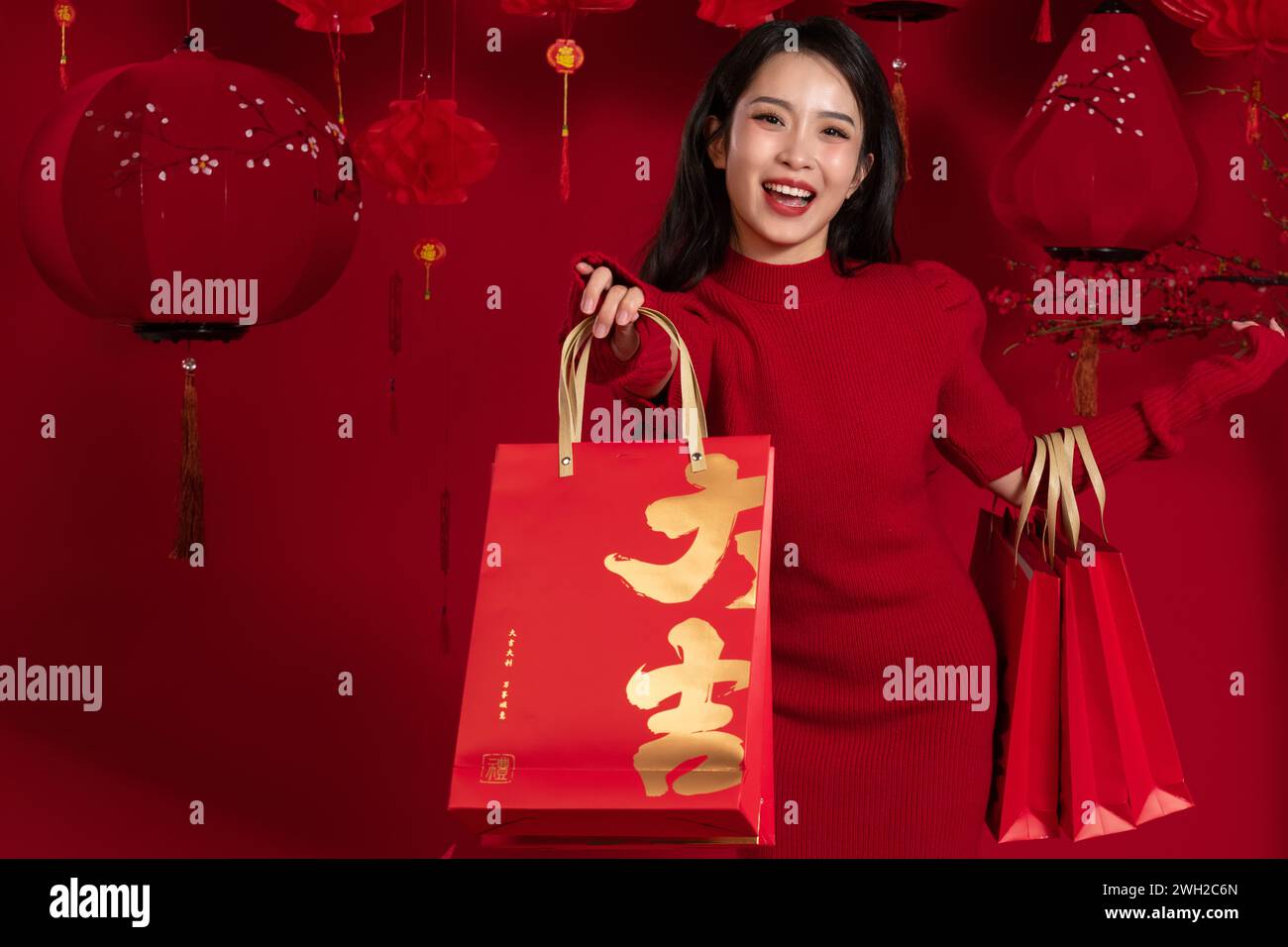Neujahrshoppen, eine junge asiatische Frau, die eine Einkaufstasche vor rotem Hintergrund hält Stockfoto