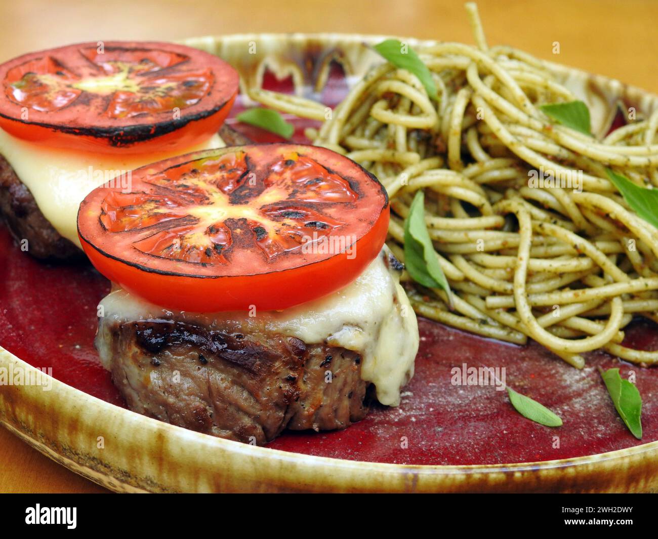Köstliches Filet Mignon gepaart mit Caprese-Salat und serviert neben Spaghetti mit aromatischer Pesto-Sauce Stockfoto