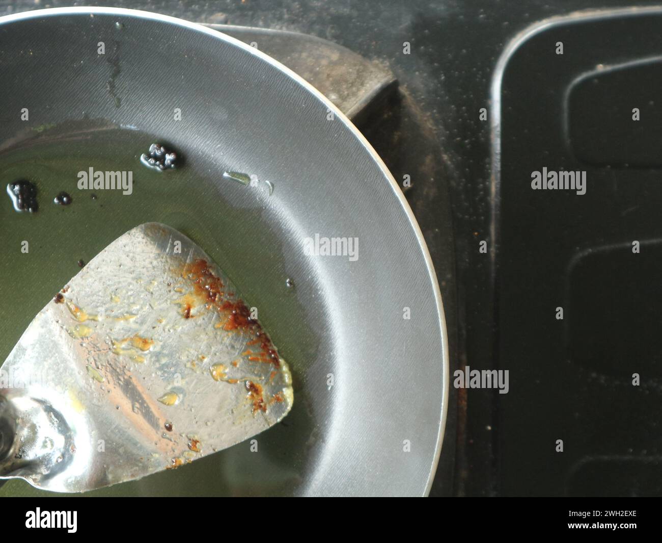 Der zum Frittieren verwendete Behälter enthält noch Öl und einen Spachtel. Bratpfanne auf einem Gasherd Stockfoto