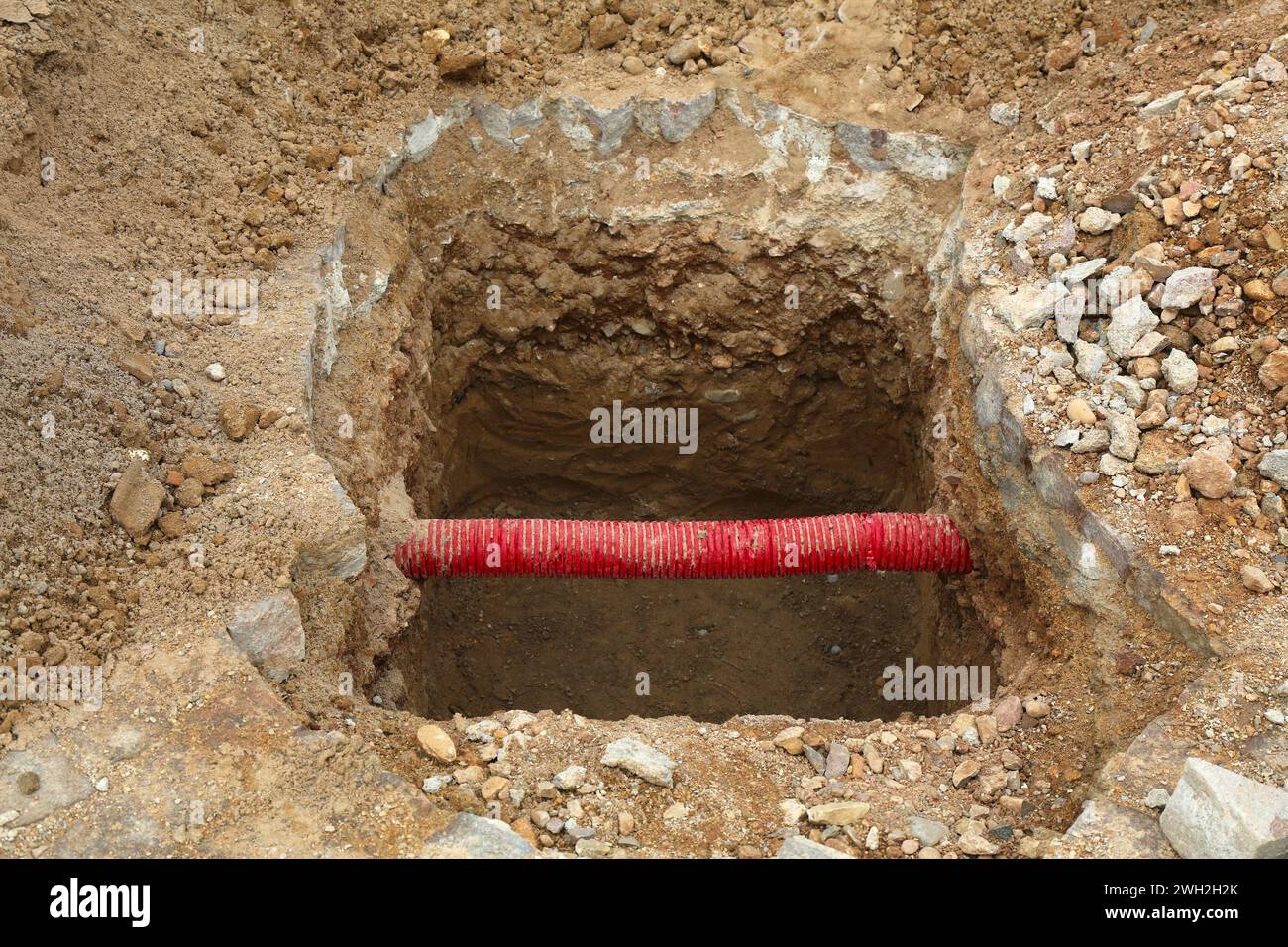 Straßeninstandhaltungsgraben mit freiliegendem rotem PVC-Schutzrohr für Erdkabel und -Drähte in Marokko. Stockfoto