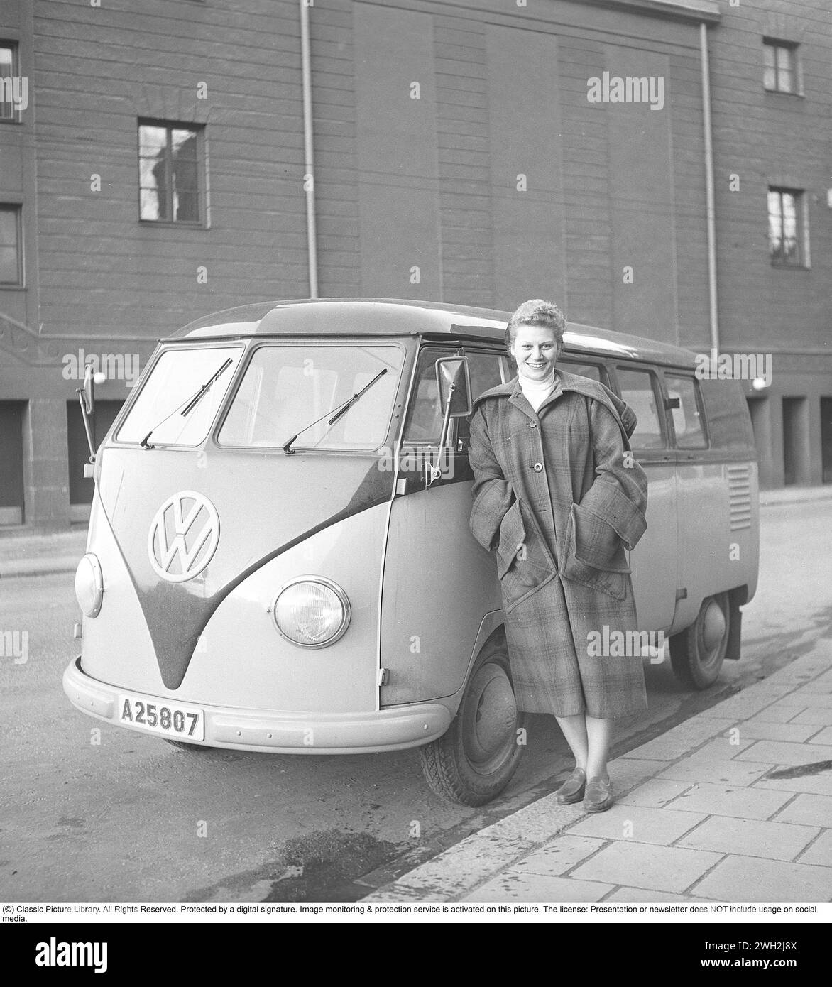 In den 1950er Jahren Eine junge Frau steht an einem Volkswagen Typ 2, der zu den Anfang der 1950er Jahre gestarteten VW-Modellen gehörte Sie trägt einen Außenmantel und das Modell ist aus Wolle und hat eine Kapuze. 1952. Kristoffersson Ref. BH80-2 Stockfoto