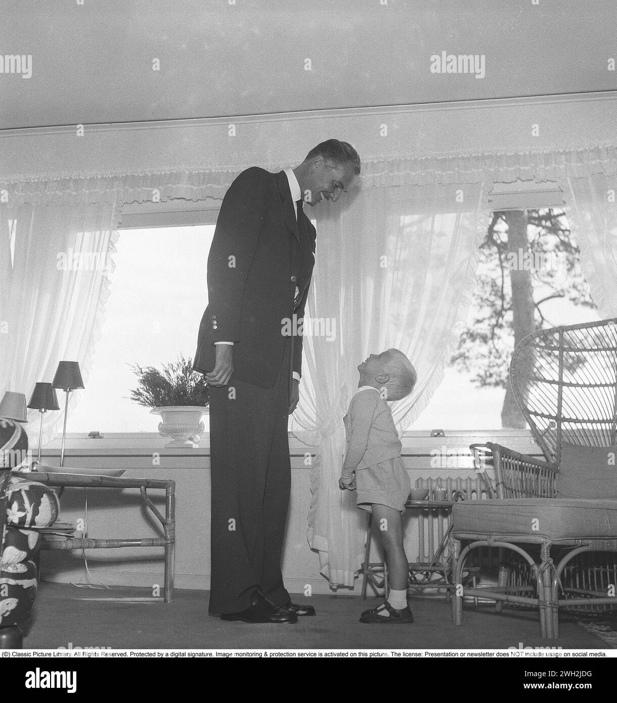 Lang und kurz in den 1950ern Gustaf Wally 1905-1966, Tänzer und Theatermann. Cousin von Raoul Wallenberg, der in Budapest verschwand und am Ende des Zweiten Weltkriegs von der Sowjetunion entführt wurde. Er war Theaterregisseur am Oscar-Theater 1941-1947 und am Södra-Theater 1949–1941. Hier zu Hause mit dem Patensohn Christan Bernadotte, dem Adoptivsohn von Graf Carl Johan Bernadotte. Schweden 1954. Kristoffersson Ref. BX20-9 Stockfoto