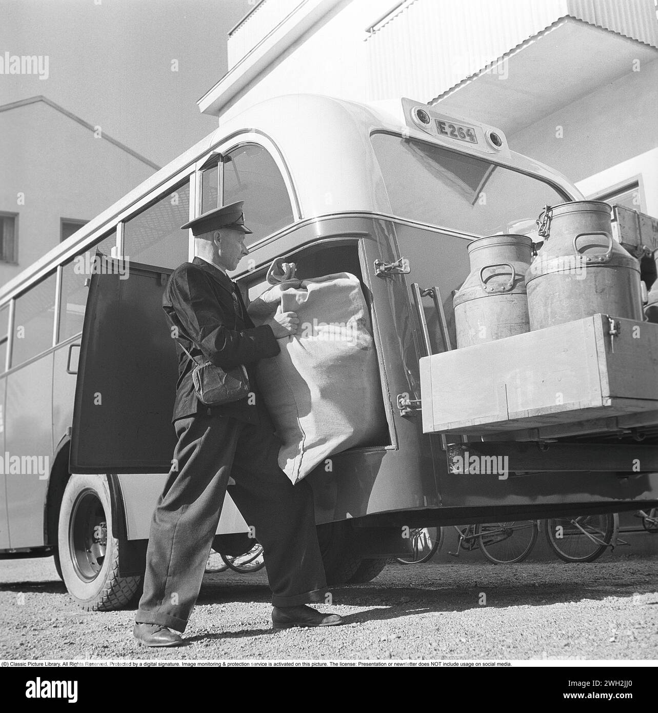 Bus in den 1940ern Ein Busfahrer lädt einen Sack Post für den Weitertransport. Neben der Post hat der Bus auch eine Ladung Milch, Lebensmittel und andere Güter für die Gemeinden im Östergötland. Schweden 1949. Kristoffersson Ref. AR40-4 Stockfoto
