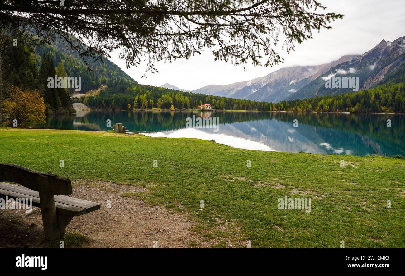 Eine Holzbank mit einem wunderschönen Blick auf den Antholzer See in den Dolomiten Italiens Stockfoto