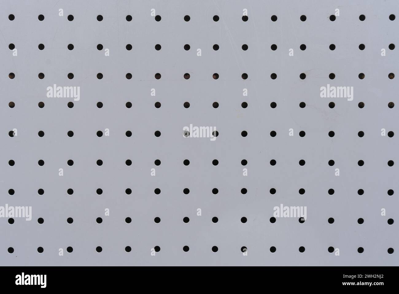 Textur von Aluminiumblechen mit regelmäßig gestanzten kreisförmigen Löchern als Hintergrund. Stockfoto