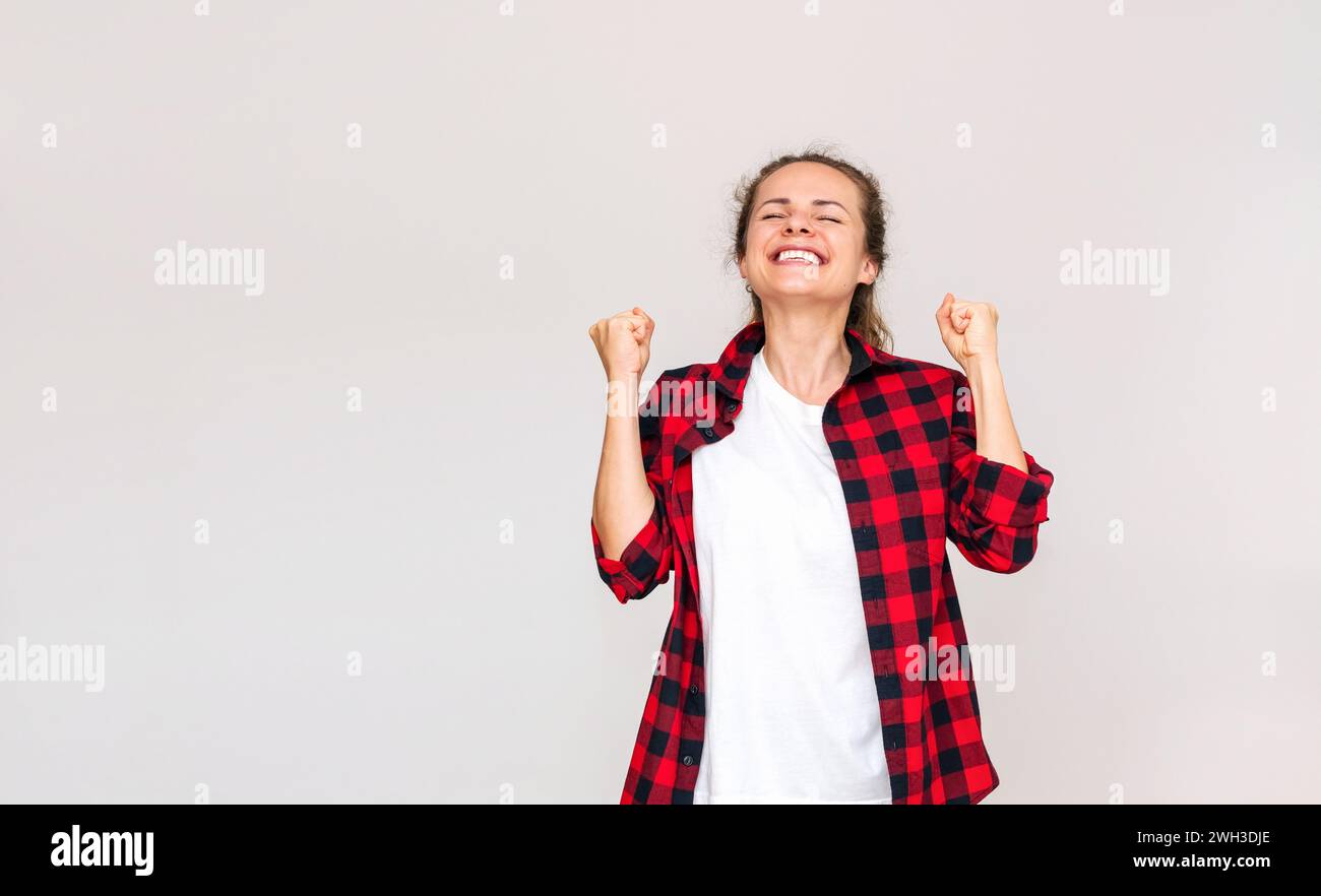 Glückliche junge brünette Frau in lässigen Kleidern, die Gefühle von Freude, Sieg und Glück zeigt. Stockfoto