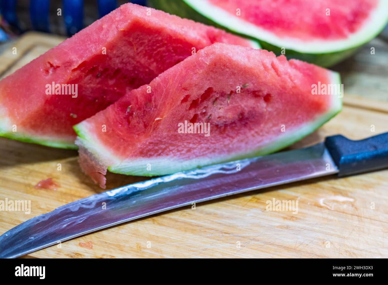 Zwei Scheiben Wassermelone auf einem Schneidebrett neben einem Messer. Stockfoto