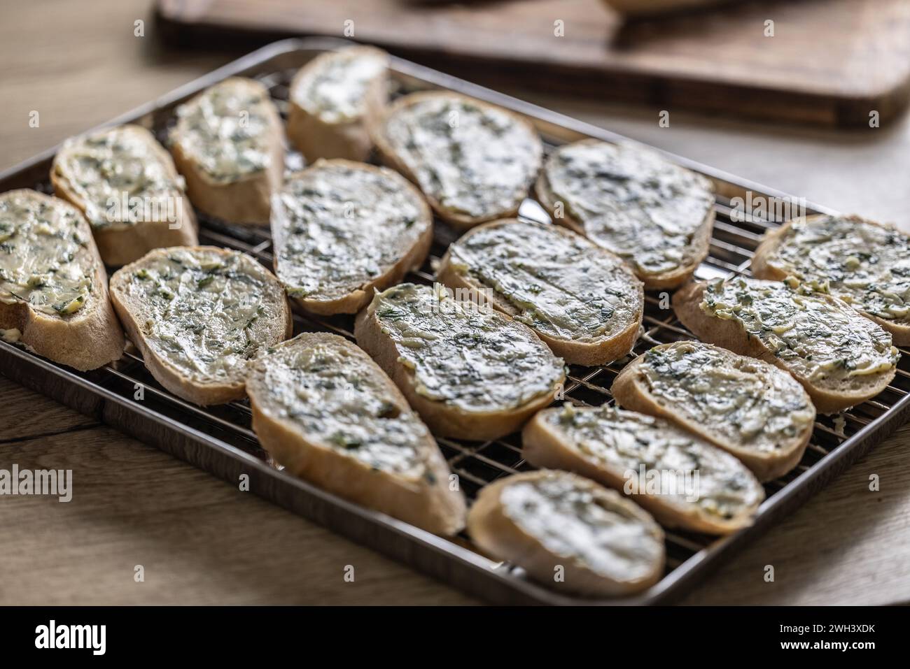 Mini-Baguettes mit Kräuter-Knoblauchbutter, fertig zum Backen auf einem Tablett. Stockfoto