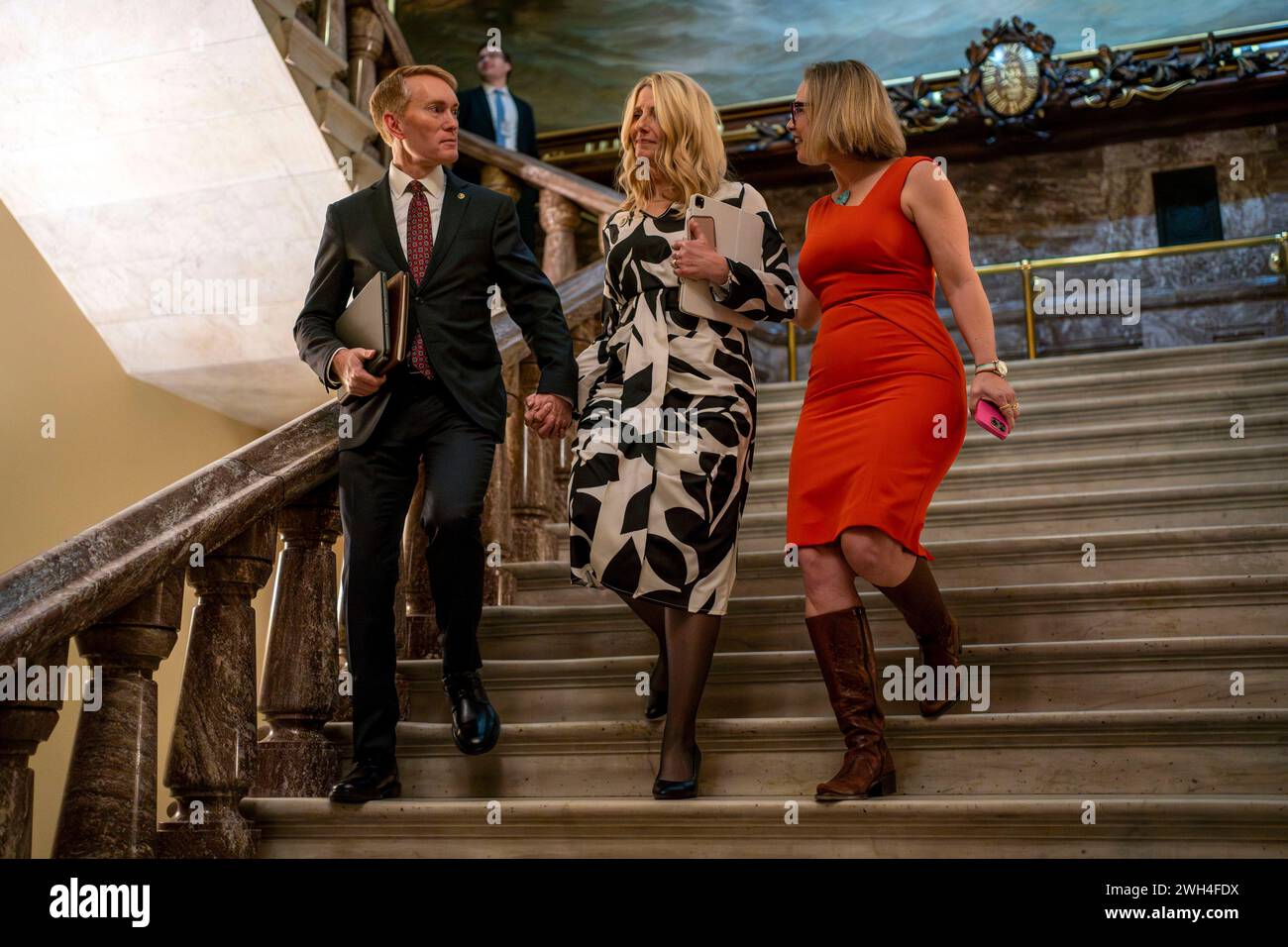 Washington, Usa. Februar 2024. Senator James Lankford, R-OK, Lankfords Ehefrau Cindy Lankford, und Senator Kyrsten Sinema, I-AZ, gehen am Mittwoch, 7. Februar 2024 eine Treppe in der Nähe der Senatskammern im US-Kapitol in Washington, DC hinunter. Lankford und Sinema waren einige der führenden Unterhändler der parteiübergreifenden Einwanderungs- und Grenzsicherheitsgesetze, die auch ausländische Hilfe für die Ukraine und Israel beinhalteten. Der Senat konnte das Gesetz nicht verabschieden, nachdem es von mehreren Republikanern und Demokraten abgeschossen wurde. Foto: Bonnie Cash/UPI Credit: UPI/Alamy Live News Stockfoto