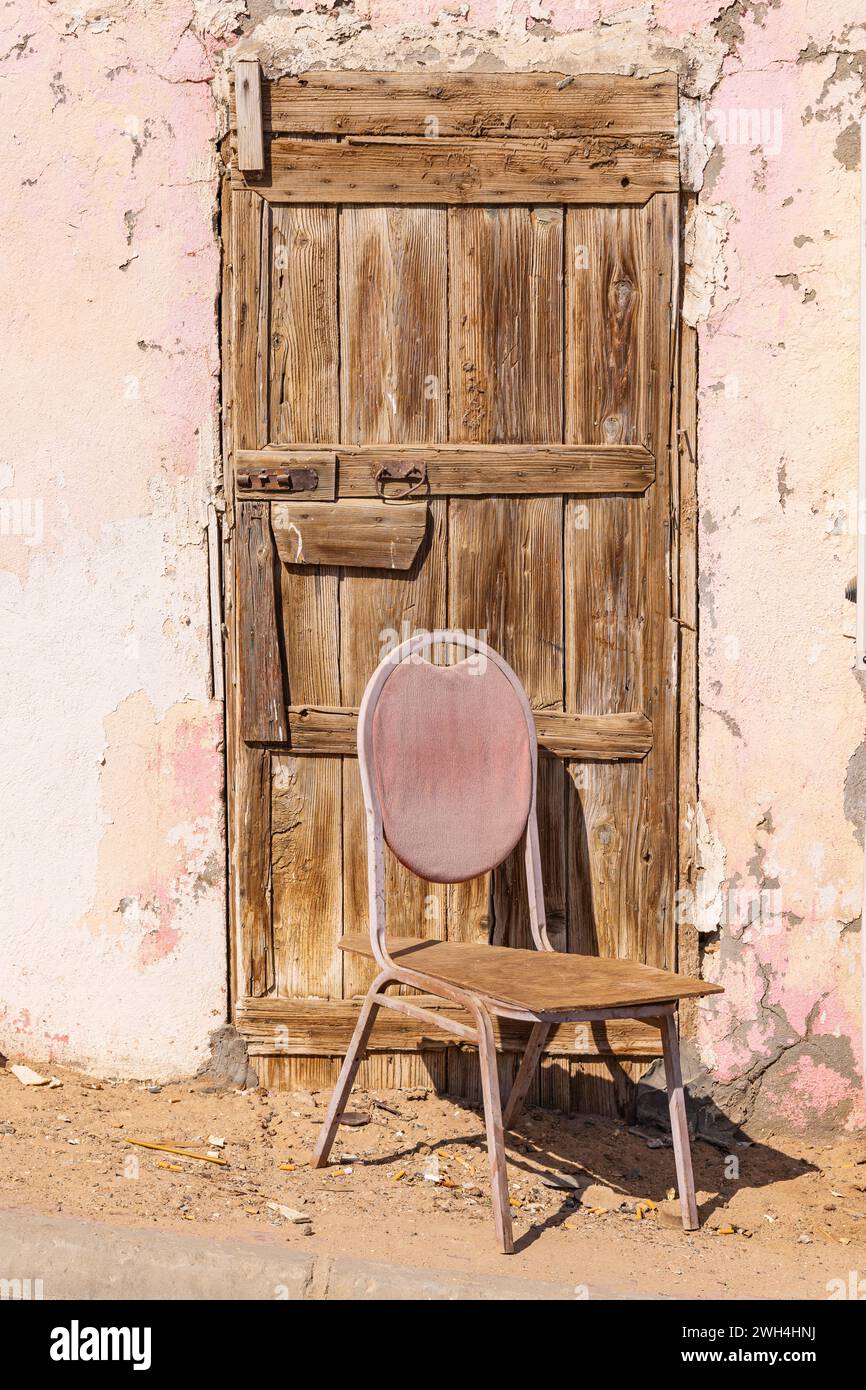 Naher Osten, Saudi-Arabien, Tabuk, Duba. Ein Stuhl vor einer alten Holztür. Stockfoto