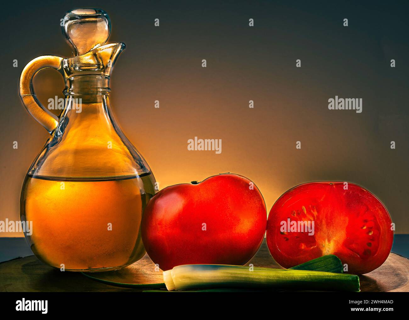 Stillleben. Eine Karaffe mit gesundem Olivenöl und leckeren halbierten Tomaten in toller, stimmungsvoller Beleuchtung. Stockfoto