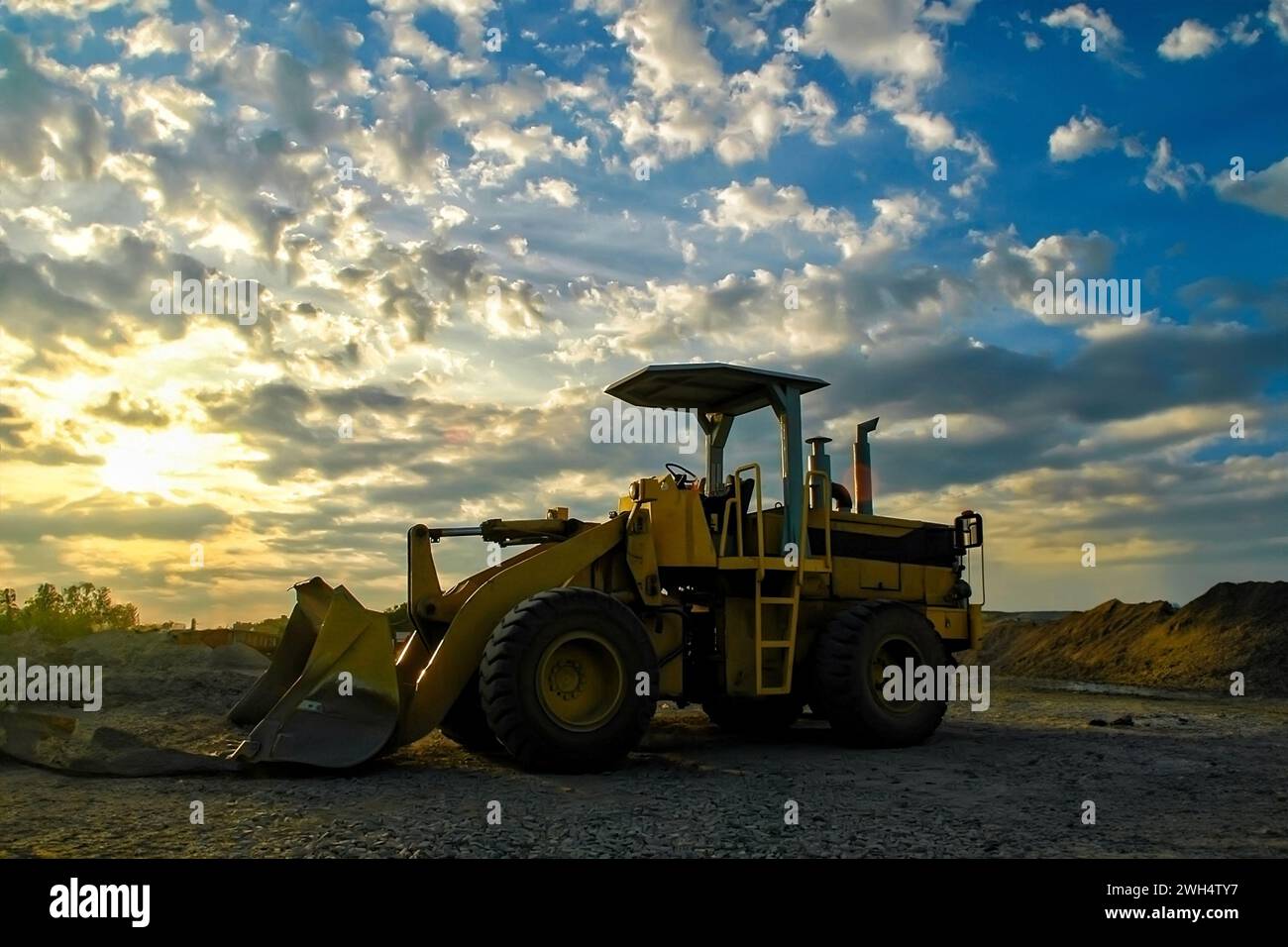 Der Bagger oder Baggerlader befindet sich auf einer Baustelle mit bewölktem Himmel in der Dämmerung Stockfoto