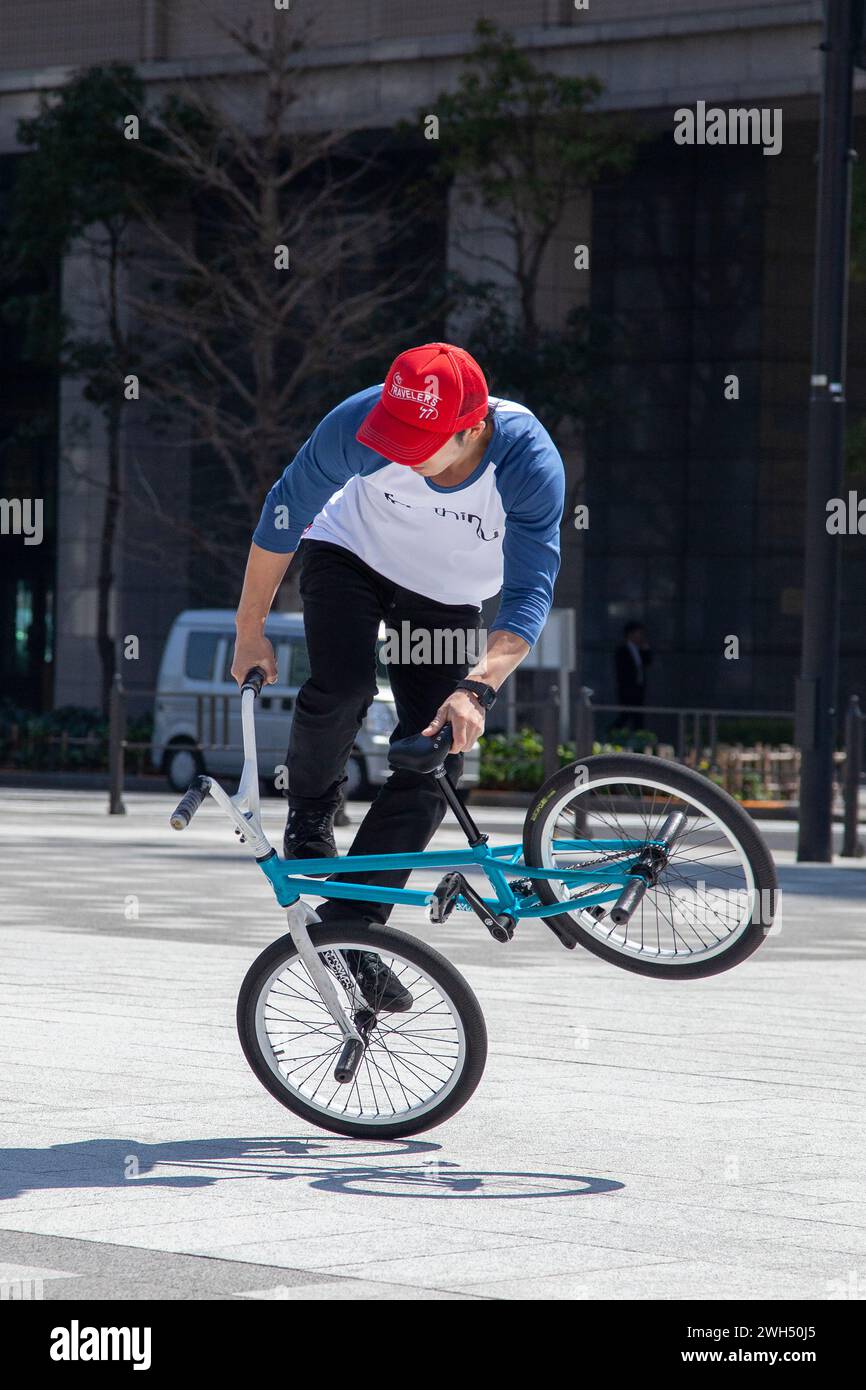 Ein japanischer BMX-Fahrer führt auf einem öffentlichen Platz mitten im Geschäftsviertel in Tokio, Japan, Tricks aus. Stockfoto