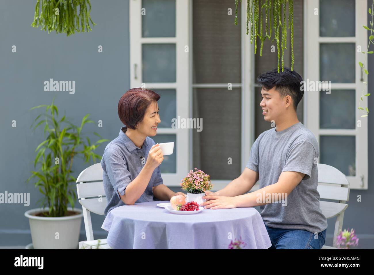 Glückliche asiatische pensionierte Mutter mit ihrem erwachsenen Sohn unterhalten sich am Morgen. Stockfoto