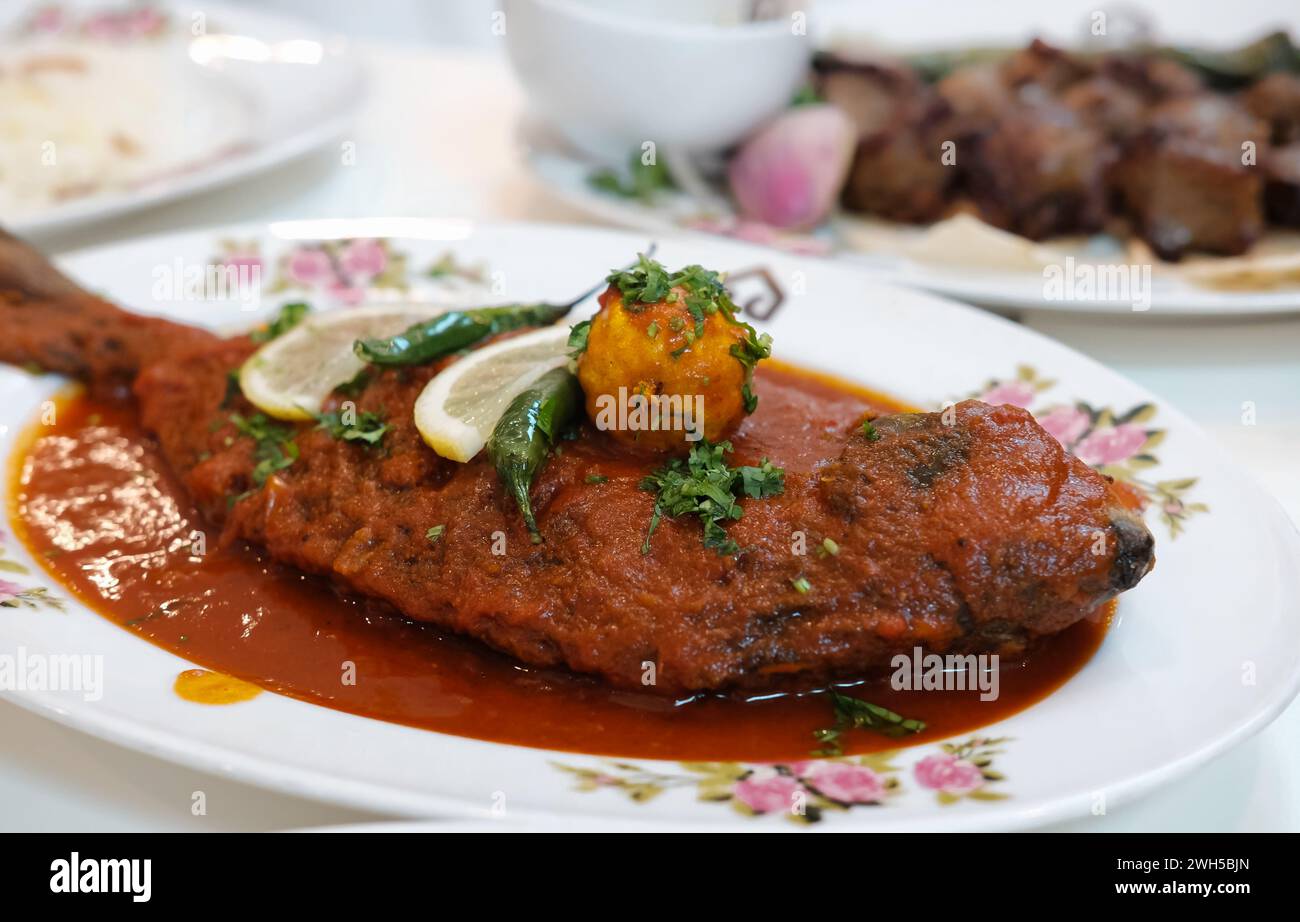 Maragat Zubaidi Fischgericht mit Tomatensauce auf einem Teller, Seer Fischcurry, traditionelles Fischcurry, spezielles Gericht. Silberpommelfische mit rotem Sause trad Stockfoto