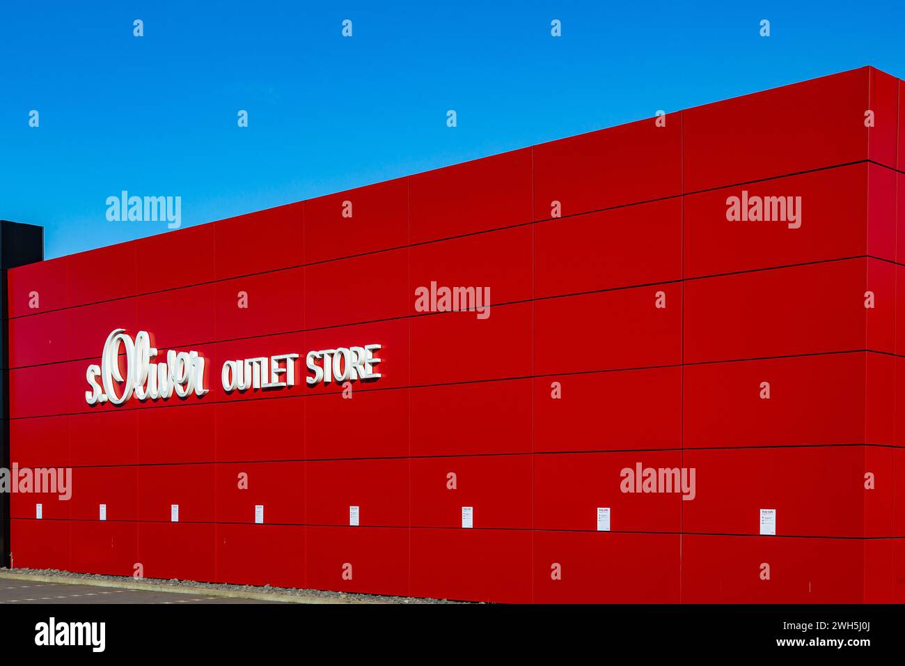 Mulheim-Karlich, Deutschland - 27. Februar 2021:: Rote Fassade des Outlet Stores s.Oliver. s.Oliver ist ein deutsches Modeunternehmen, das Kleidung, Schuhe und Schuhe verkauft Stockfoto