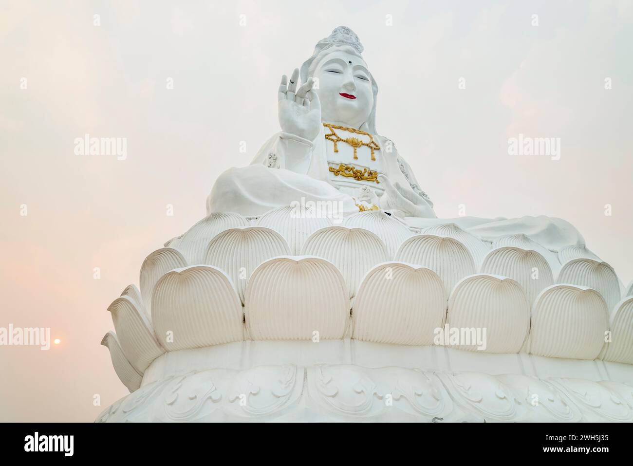 Die Sonne untergeht, gegenüber der riesigen großen Struktur des „Großen Buddha“ von Chiang Rai, riesiges, hohes, weißes, zeitgenössisches buddhistisches Gebäude, das sich hoch aufragt Stockfoto