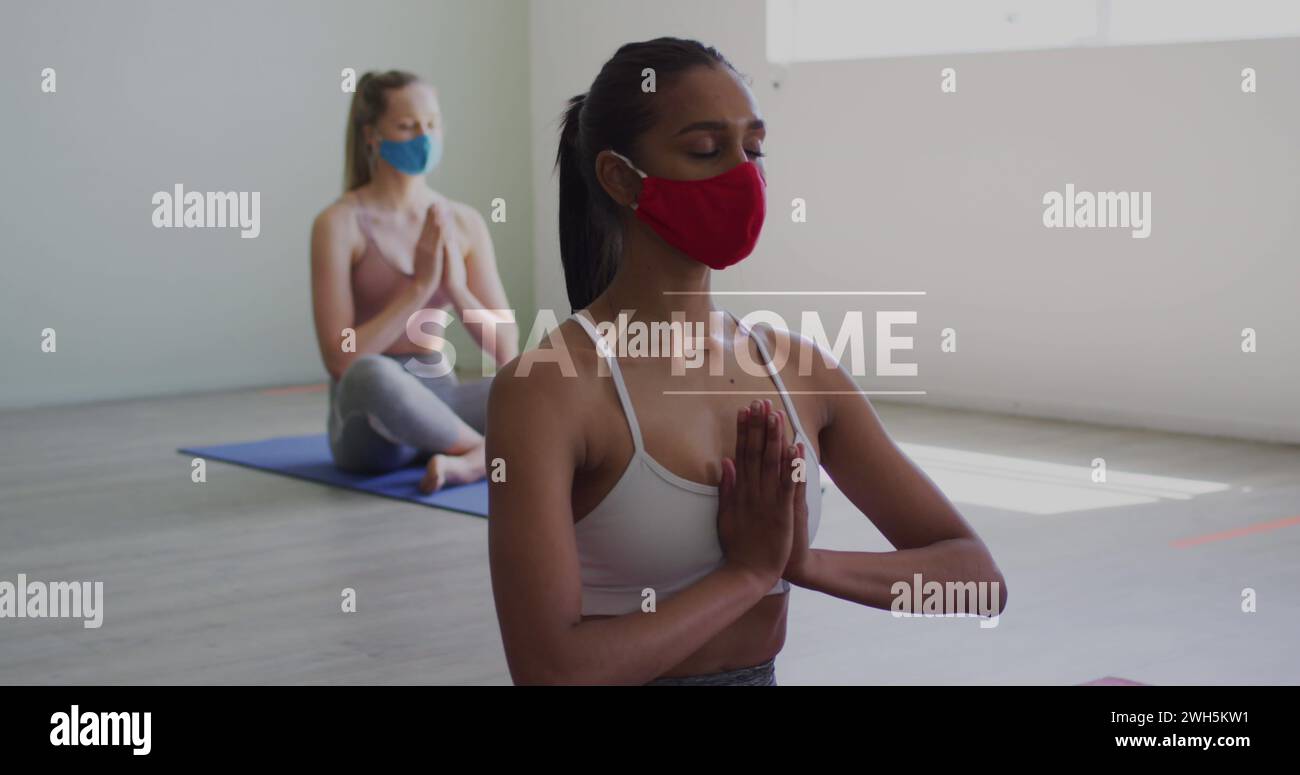 Coronavirus-Konzepttexte gegen zwei Frauen mit Gesichtsmasken beim Yoga Stockfoto