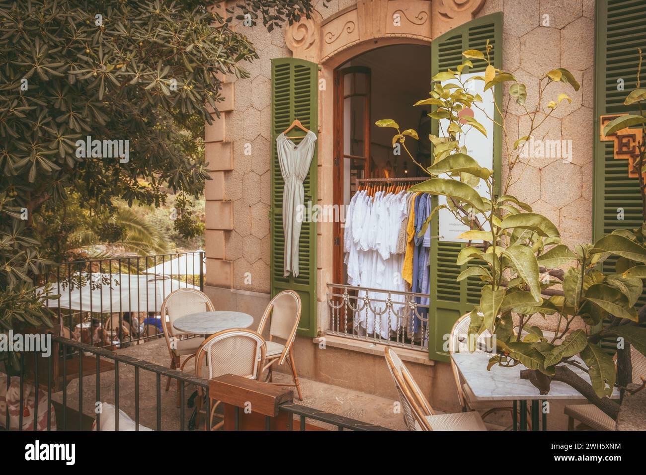 Ein ruhiger Außenbereich mit stilvollem Eisenzaun und einer Boutique mit modischer Kleidung Stockfoto