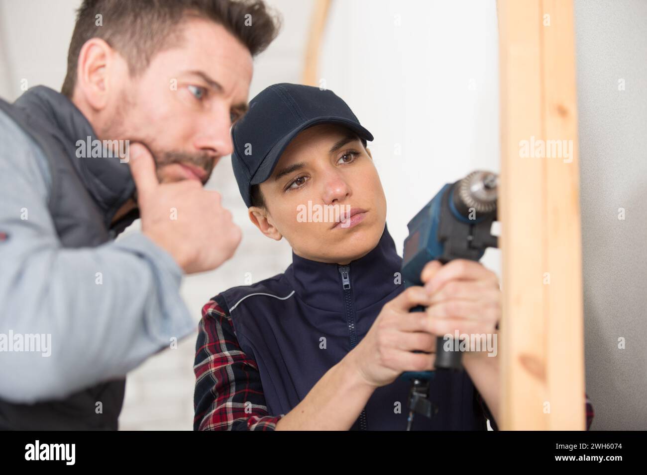 Schreinerauszubildende mit Bohrmaschine unter Aufsicht Stockfoto