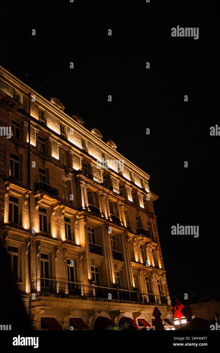 Ein Hotelgebäude glänzt nachts mit Eleganz, beleuchtet durch stilvolle Wandwaschleuchten, die moderne Architektur und elegantes Design bieten. Stockfoto