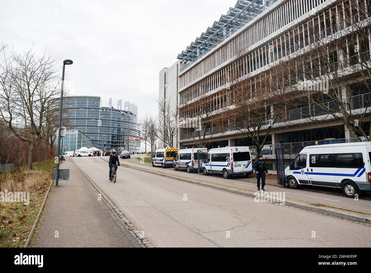 Straßburg, Frankreich - 6. Februar 2024: Bau- und Polizeiwagen als Demonstranten mit Traktoren blockieren den Eingang zum EU-Parlament und protestieren gegen importierte Lebensmittelstandards und neue GVO Stockfoto