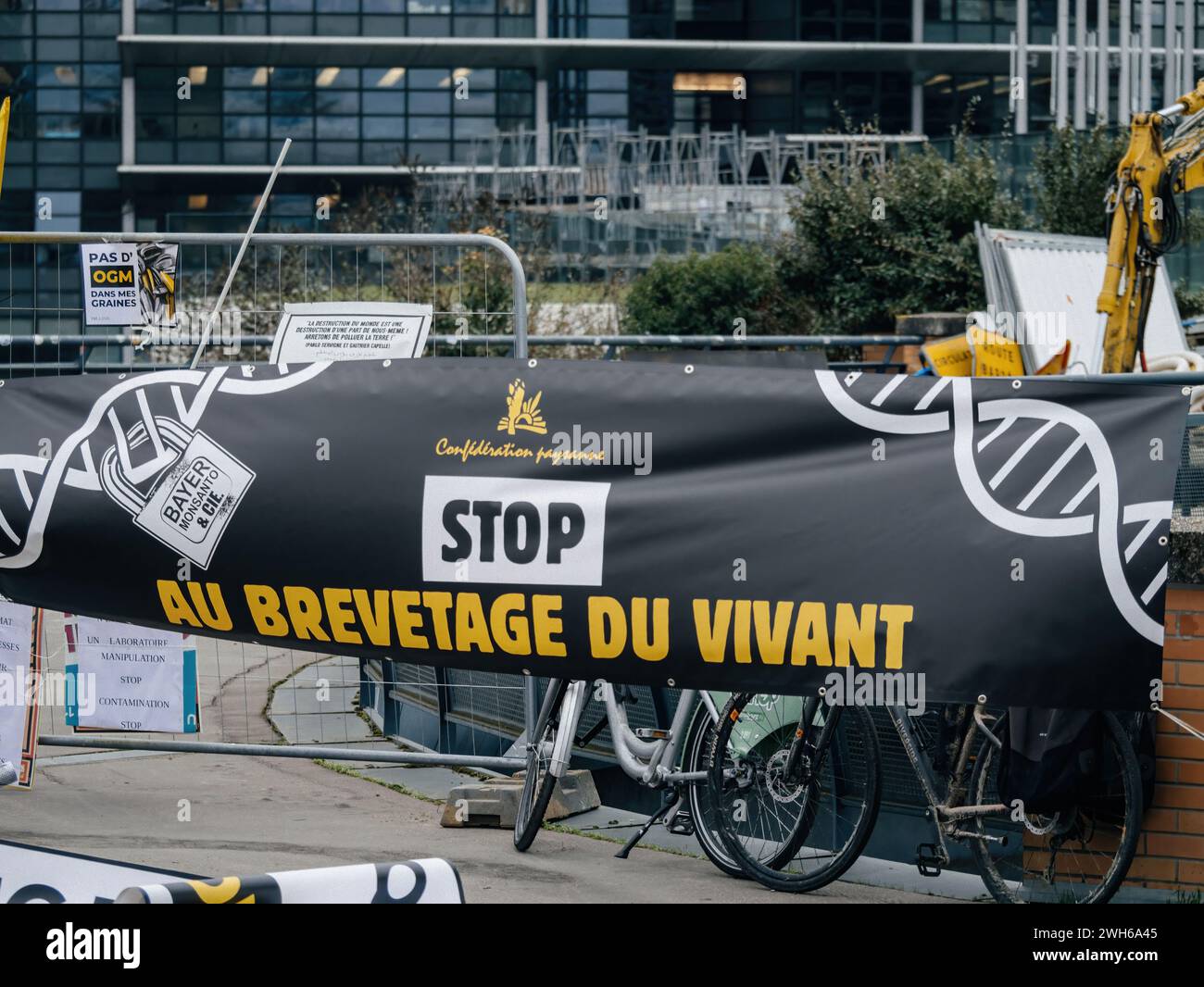 Straßburg, Frankreich - 6. Februar 2024: Demonstranten mit Traktoren blockieren den Eingang zum EU-Parlament, halten ein „Stop“-Plakat und protestieren gegen importierte Lebensmittel mit niedrigeren Standards und neue GVO Stockfoto