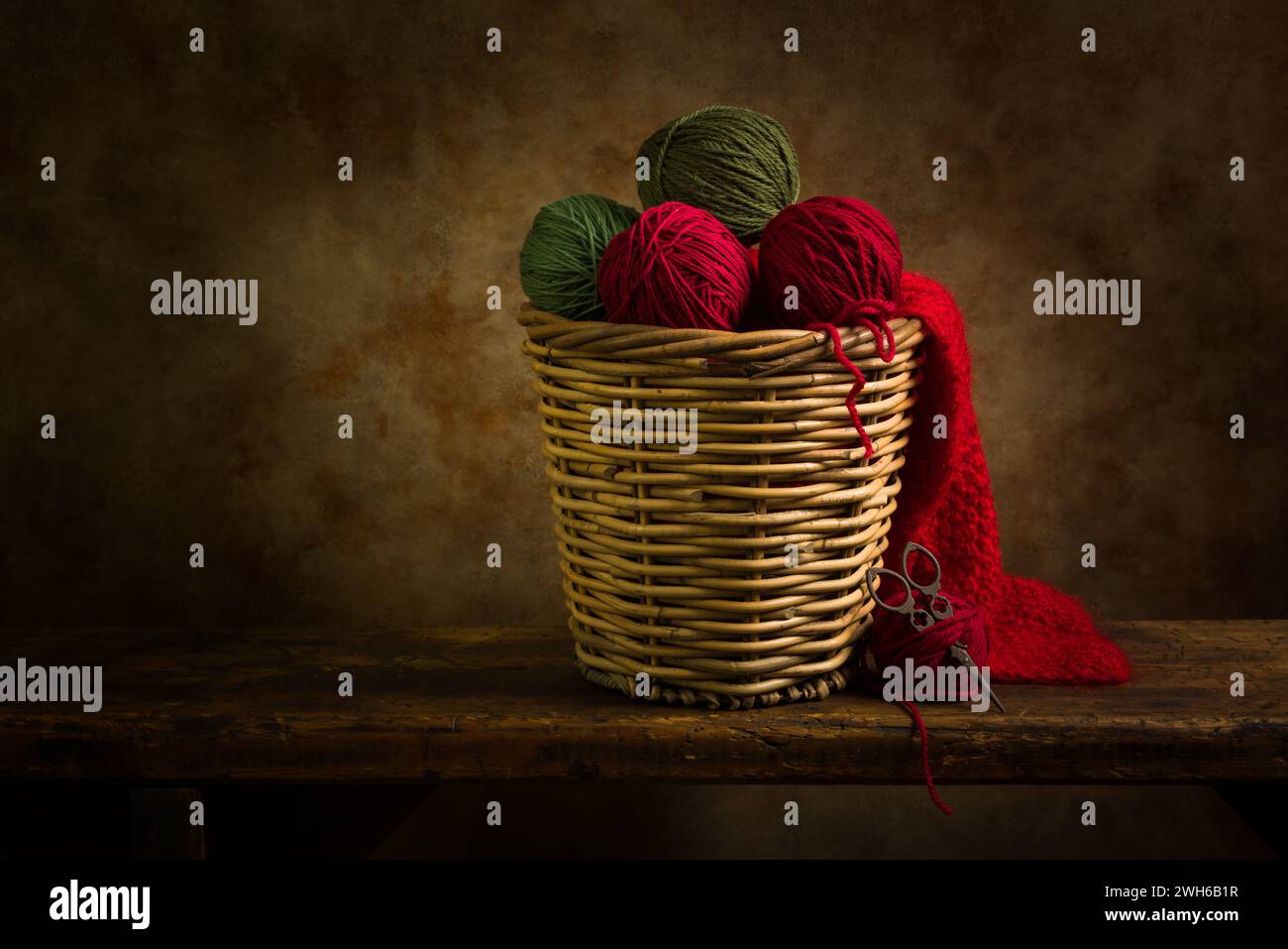 Korb mit grünen und roten Wollkugeln auf einem rustikalen alten Holzregal. Dies ist für das digitale Compositing geeignet. Stockfoto