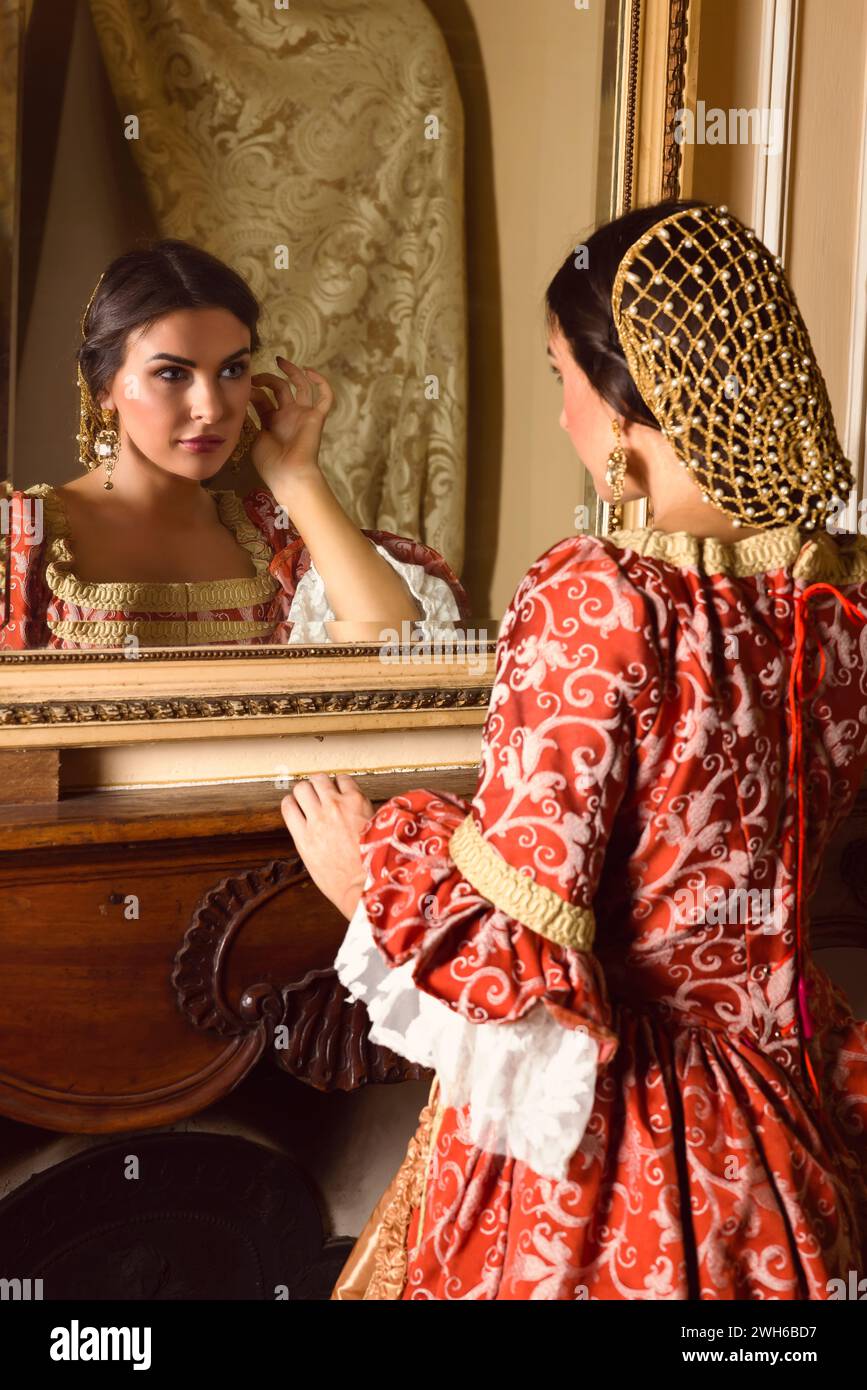 Schöne Frau in Renaissance-Kleid Blick in einen antiken goldenen Spiegel in ihrem Schloss Stockfoto