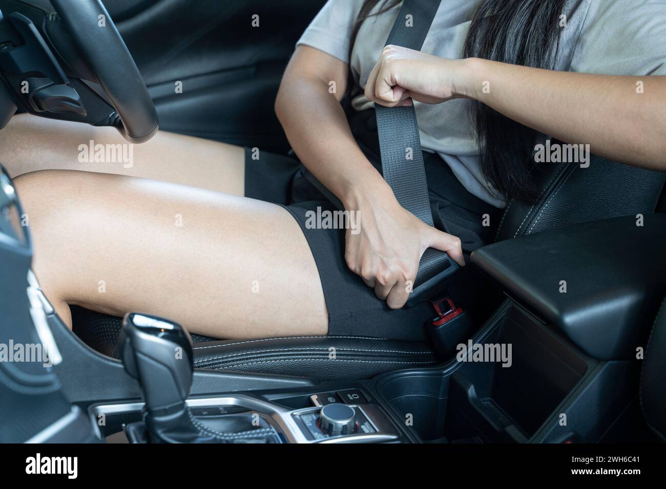 Nahaufnahme einer Handfrau, die im Auto den Sicherheitsgurt zieht; Konzept der Fahrzeugsicherheit. Stockfoto