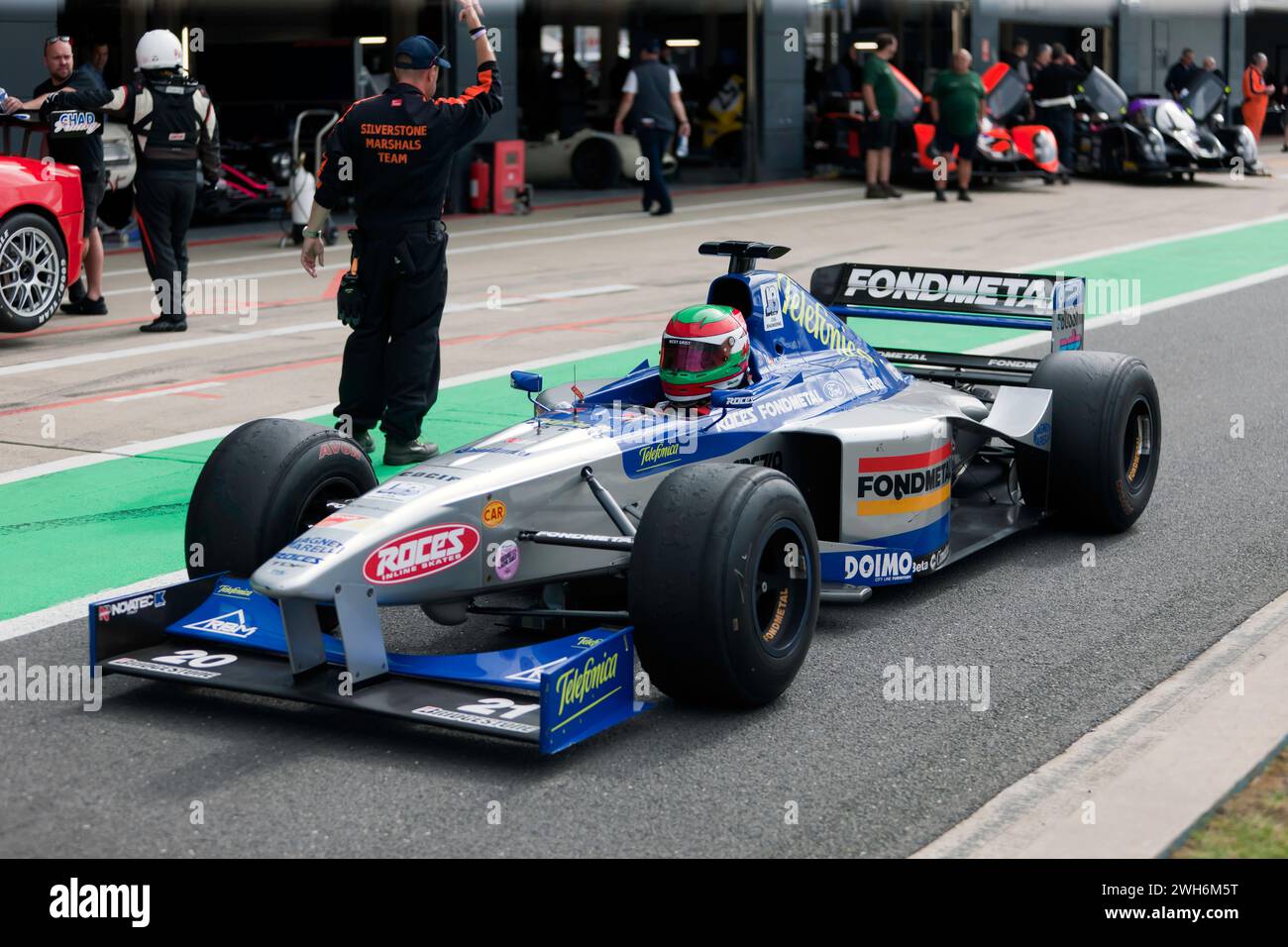 Ein 1999er Minardi M198 Formel-1-Auto, das während der Demonstration zum 75. Jahrestag des Grand Prix in Silverstone auf der internationalen Pit Lane fuhr Stockfoto