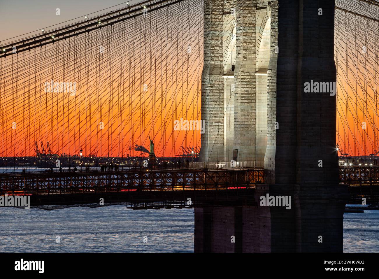 Brooklyn Bridge und Freiheitsstatue bei Sonnenuntergang beleuchtet. Nahaufnahme von zwei historischen Wahrzeichen von New York City Stockfoto
