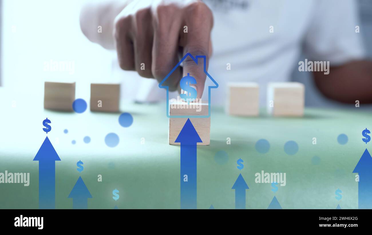 Ein Mann, der Holzwürfel mit einer Hausfigur drückt. Das Konzept des Verkaufs eines Hauses mit einem hohen Verkaufsniveau. Stockfoto