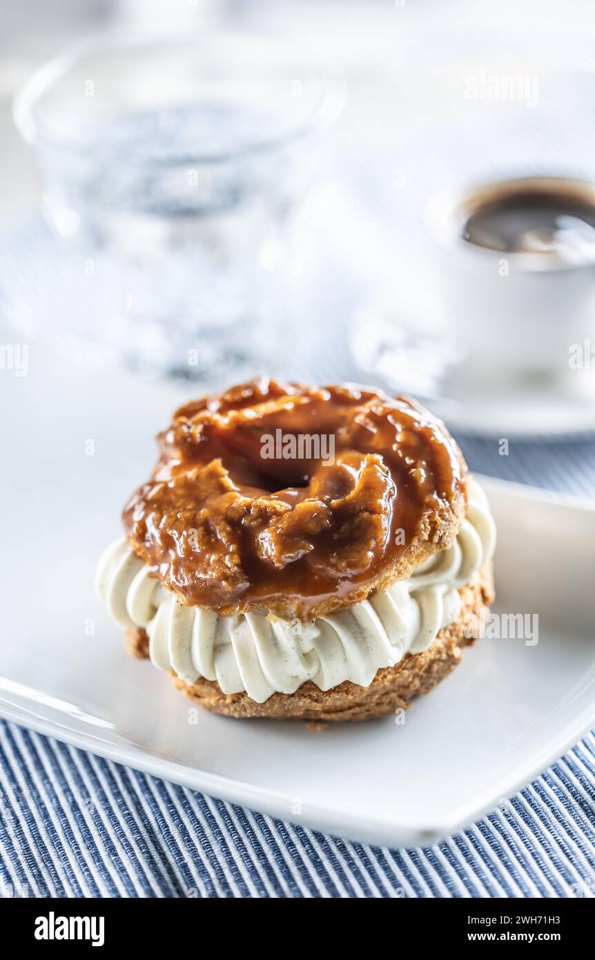 Veternik: Süßer Donut, typisch slowakischer süßer Kuchen mit Sahnefüllung, garniert mit Karamell auf einem Teller in einem Café. Stockfoto