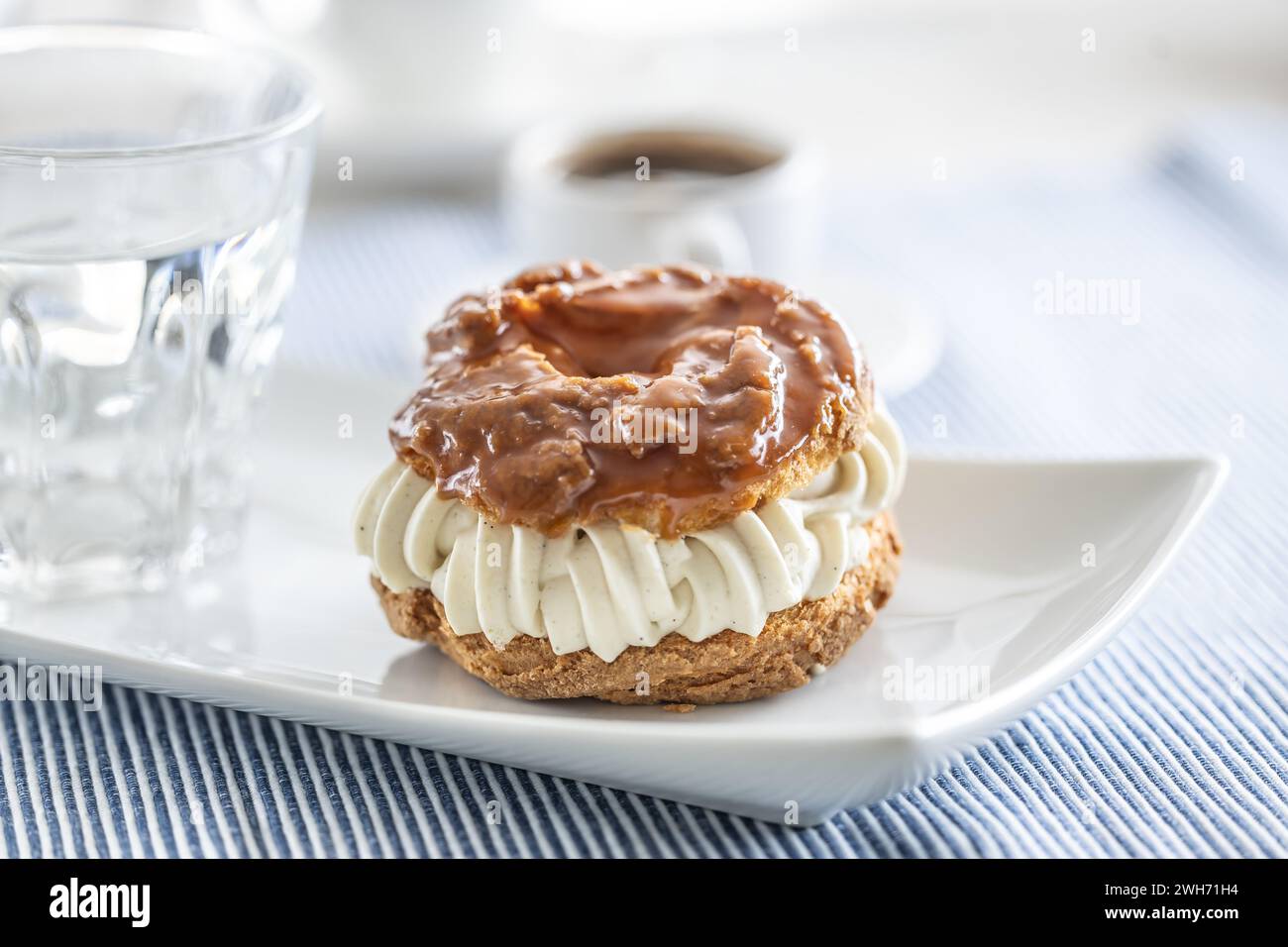 Veternik: Süßer Donut, typisch slowakischer süßer Kuchen mit Sahnefüllung, garniert mit Karamell auf einem Teller in einem Café. Stockfoto