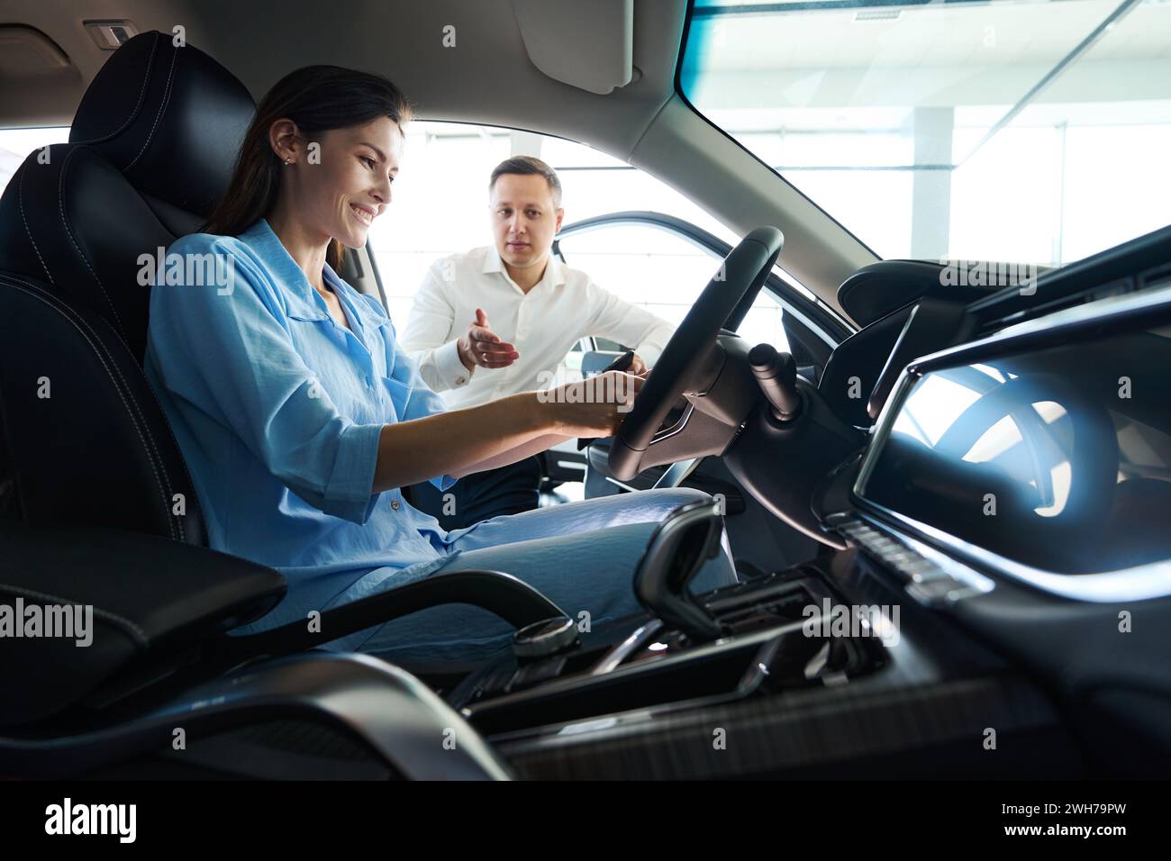 Der Berater eines Autohändlers präsentiert dem Kunden ein Fahrzeug Stockfoto