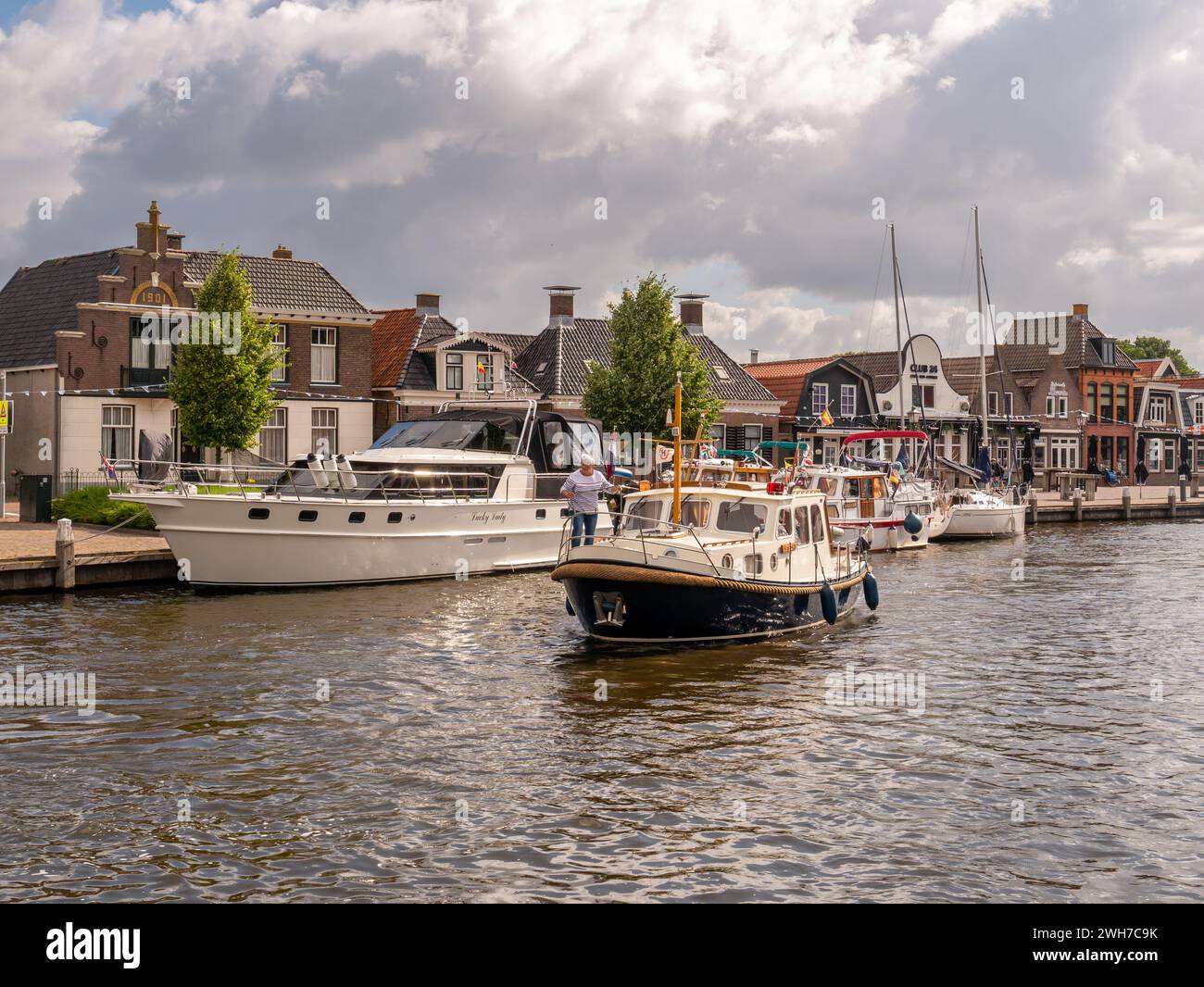 Motorboot auf der Suche nach Anlegeplatz im Het Dok Kanal in der Altstadt von Lemmer, Friesland, Niederlande Stockfoto